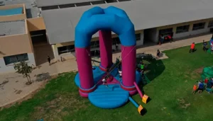 מבט אווירי על מתקן מתנפח שילדים משחקים עליו בחוץ, ליד בניין על דשא ירוק.